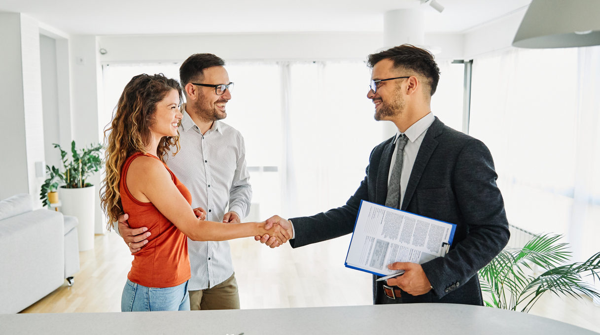 Real estate agent with couple shaking hands closing a deal